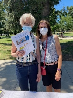 two women wearing face masks holding a flyer