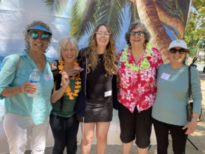 group of women smiling in front of tropical backdrop