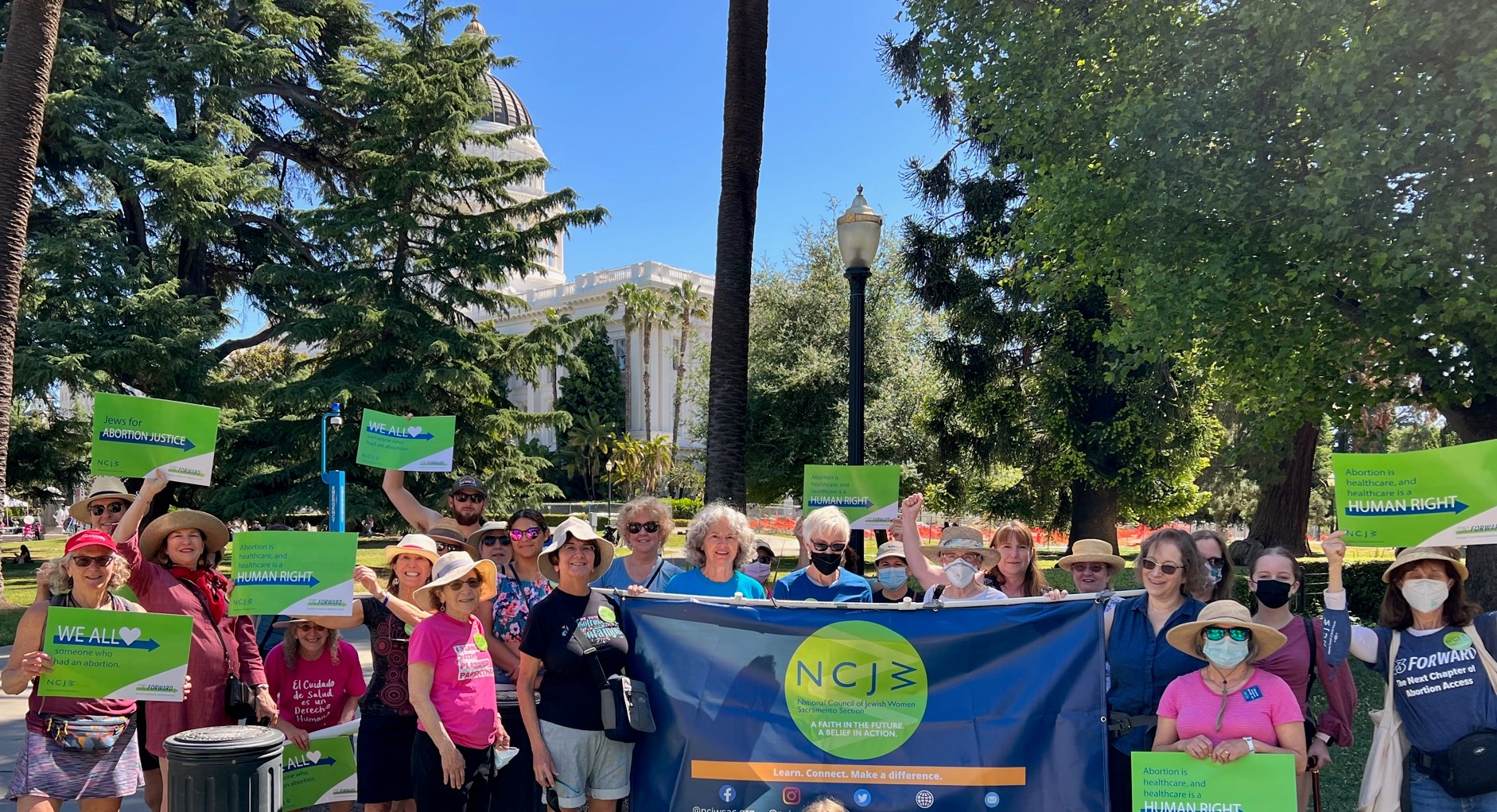 ncjw sacramento members pose with banners in front of the California state capitol